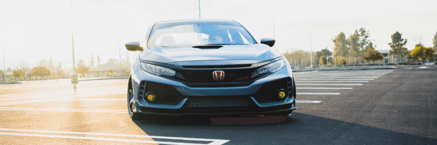 Automotive Repair & Tire Shop Oakville, ON - Sil’s Auto Care Centre A grey Honda Civic with yellow fog lights is parked in an empty car park on a sunny day, facing the camera. Trees and lamp posts are visible in the background—perfect for anyone searching “Honda Mechanic Near Me.”. | Call Us Today At +1 (905) 823-2626