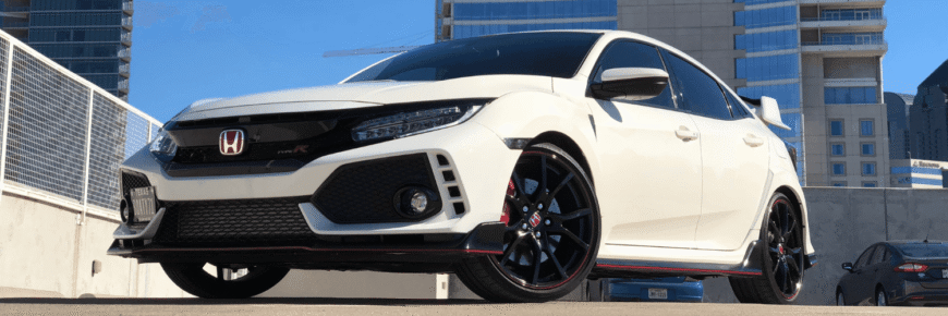 Automotive Repair & Tire Shop Oakville, ON - Sil’s Auto Care Centre A white Honda Civic Type R hatchback with black and red accents is parked outdoors in a city setting, with modern high-rise buildings in the background. This sporty model is ready for its next Service B1 Honda maintenance. | Call Us Today At +1 (905) 823-2626