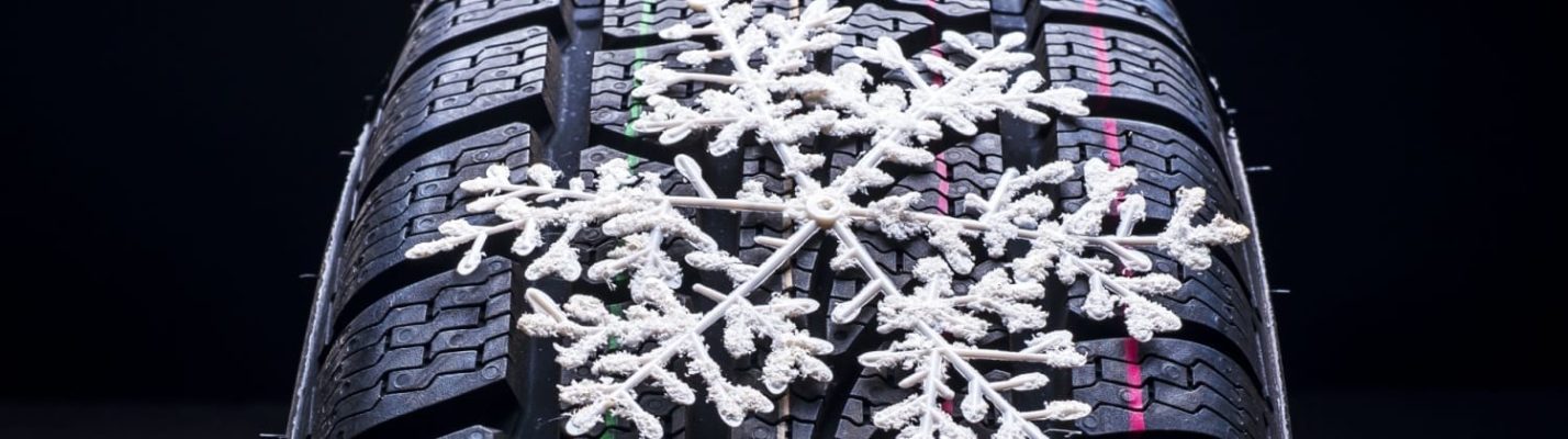 Automotive Repair & Tire Shop Oakville, ON - Sil’s Auto Care Centre A close-up of a winter tyre shows a white snowflake decoration resting on its tread pattern, highlighting the tyre's suitability for snowy or icy conditions. | Call Us Today At +1 (905) 823-2626