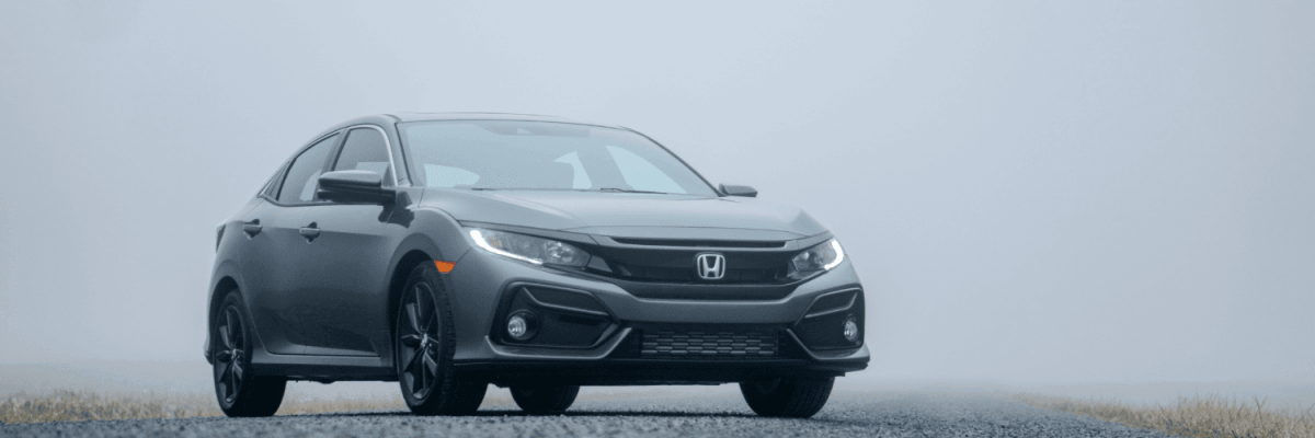 Automotive Repair & Tire Shop Oakville, ON - Sil’s Auto Care Centre A grey Honda saloon parked on an empty road surrounded by fog, with low visibility and a faint suggestion of grass on either side—perfect for drivers seeking a reliable drive or searching for a Honda Service Centre Near Me. | Call Us Today At +1 (905) 823-2626