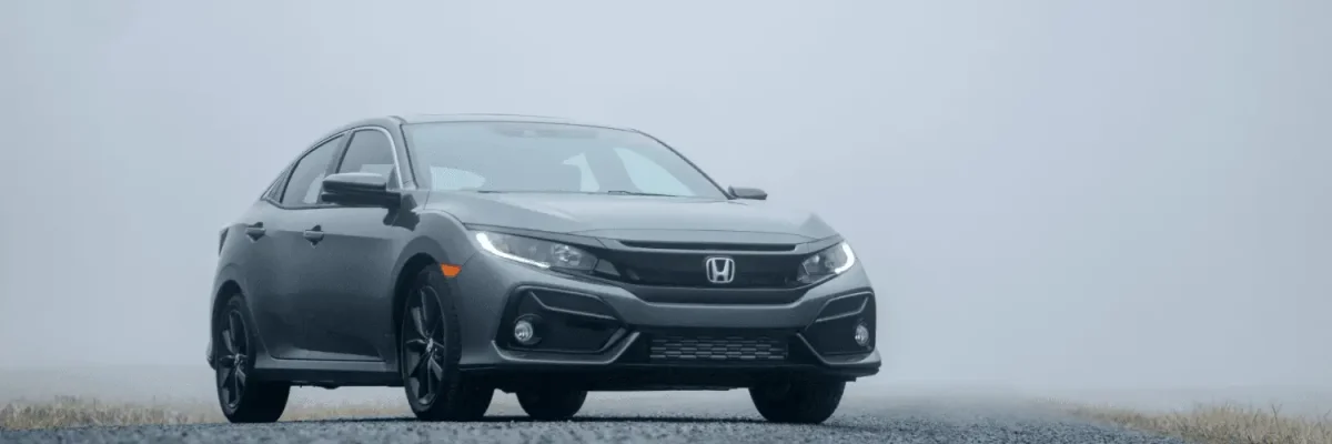 Automotive Repair & Tire Shop Oakville, ON - Sil’s Auto Care Centre A grey Honda saloon parked on an empty road surrounded by fog, with low visibility and a faint suggestion of grass on either side—perfect for drivers seeking a reliable drive or searching for a Honda Service Centre Near Me. | Call Us Today At +1 (905) 823-2626