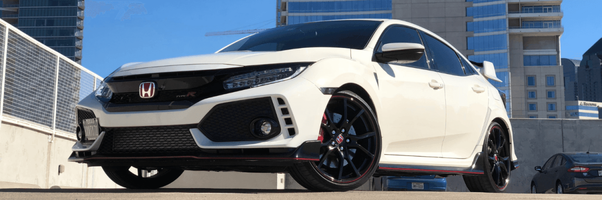 Automotive Repair & Tire Shop Oakville, ON - Sil’s Auto Care Centre A white Honda Civic Type R hatchback with black and red accents is parked outdoors in a city setting, with modern high-rise buildings in the background. This sporty model is ready for its next Service B1 Honda maintenance. | Call Us Today At +1 (905) 823-2626
